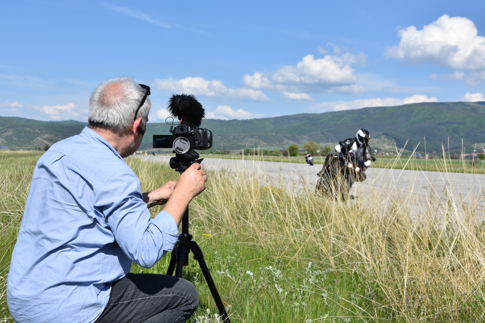 videographer filming motorcycles racing on outside location