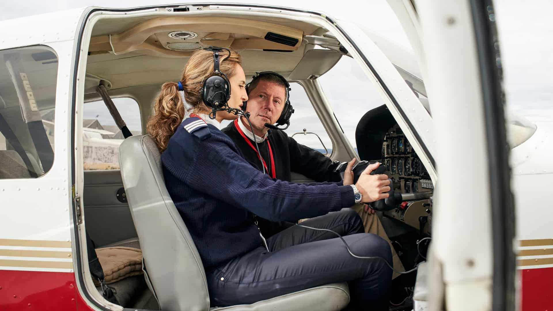 flying instructor and trainee in a plane going over plane controls